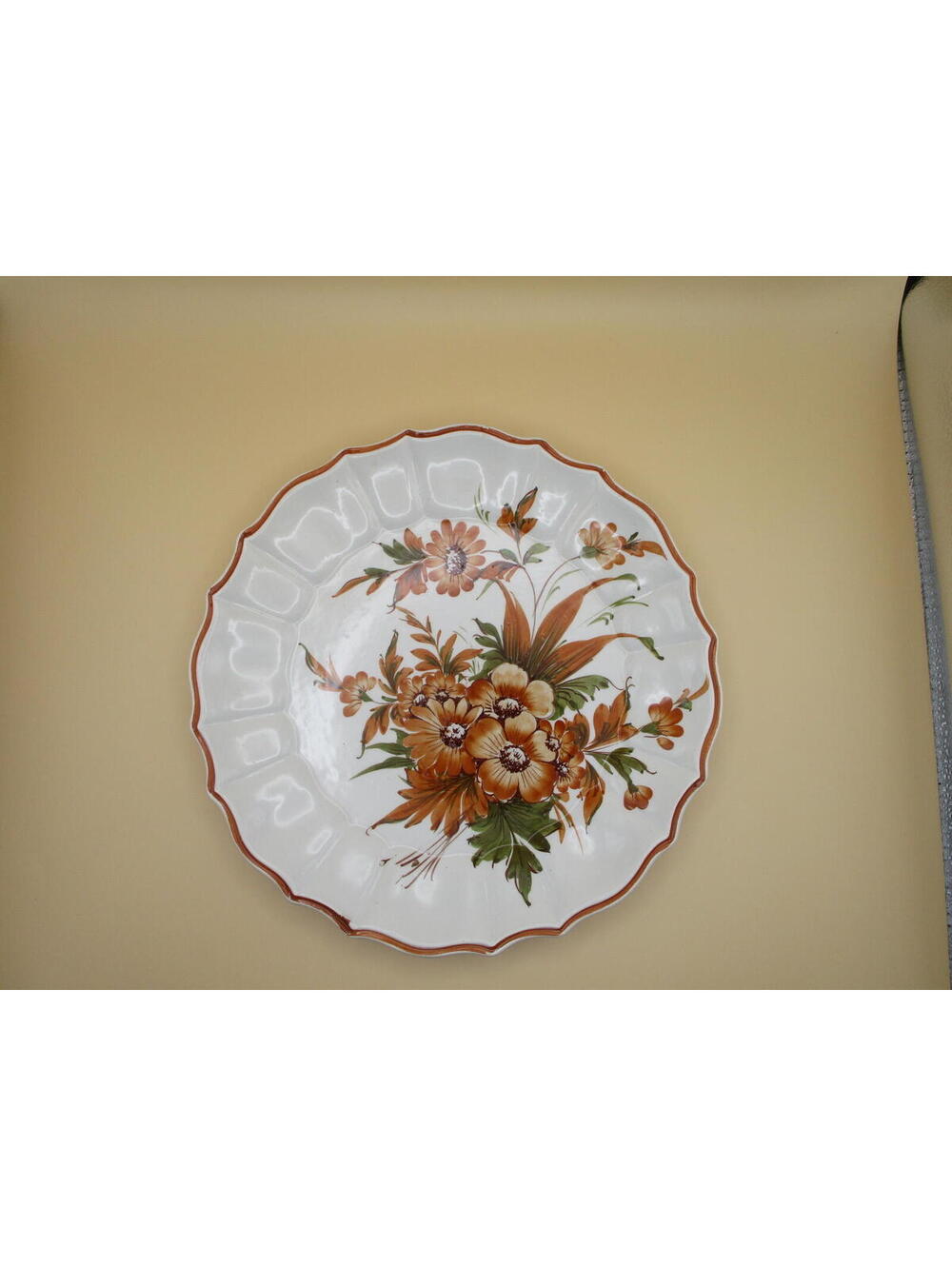 A vintage hand-painted Italian ceramic decorative plate with floral motifs.